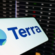 A phone with the Terra logo is shown against a backdrop of a screen showing market numbers.